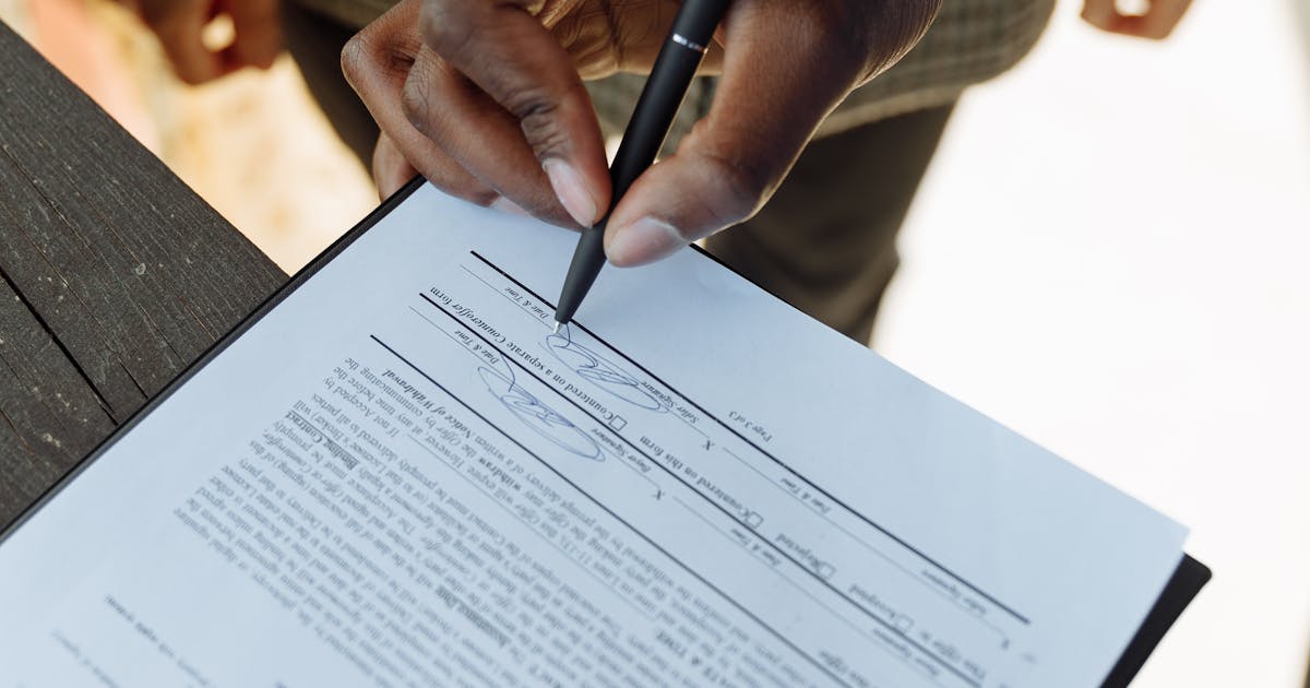 Close-up of a contract document being signed on an office desk
