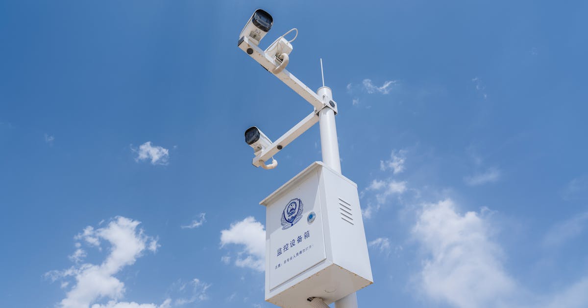 Multiple security cameras on a pole under a blue sky