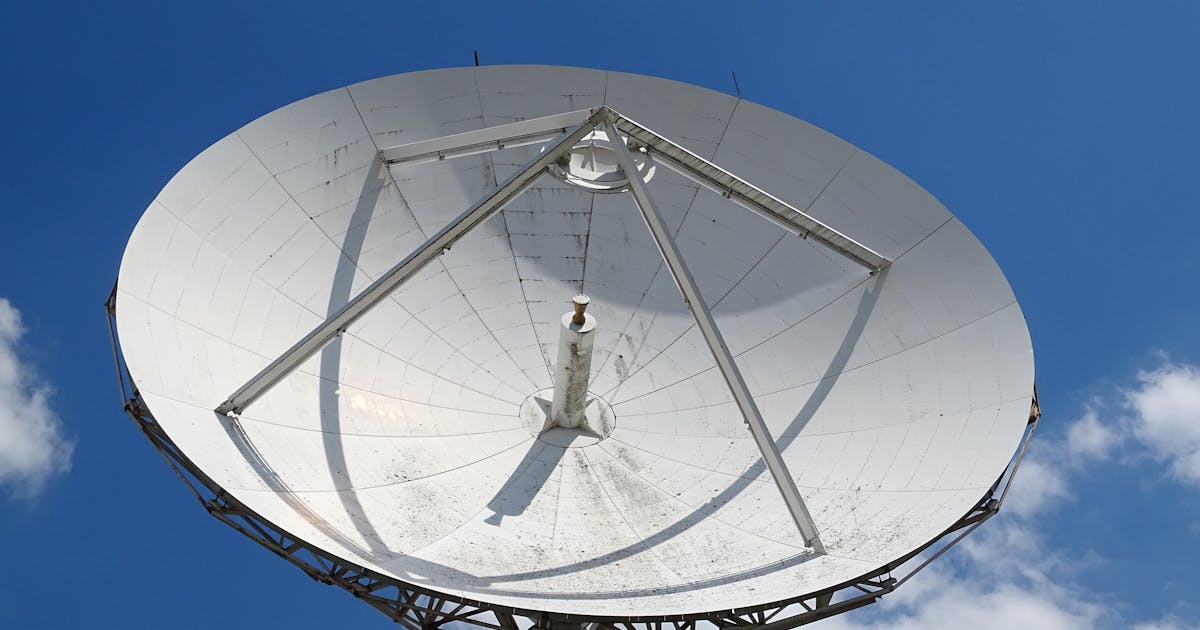 Large satellite dish under a blue sky with clouds
