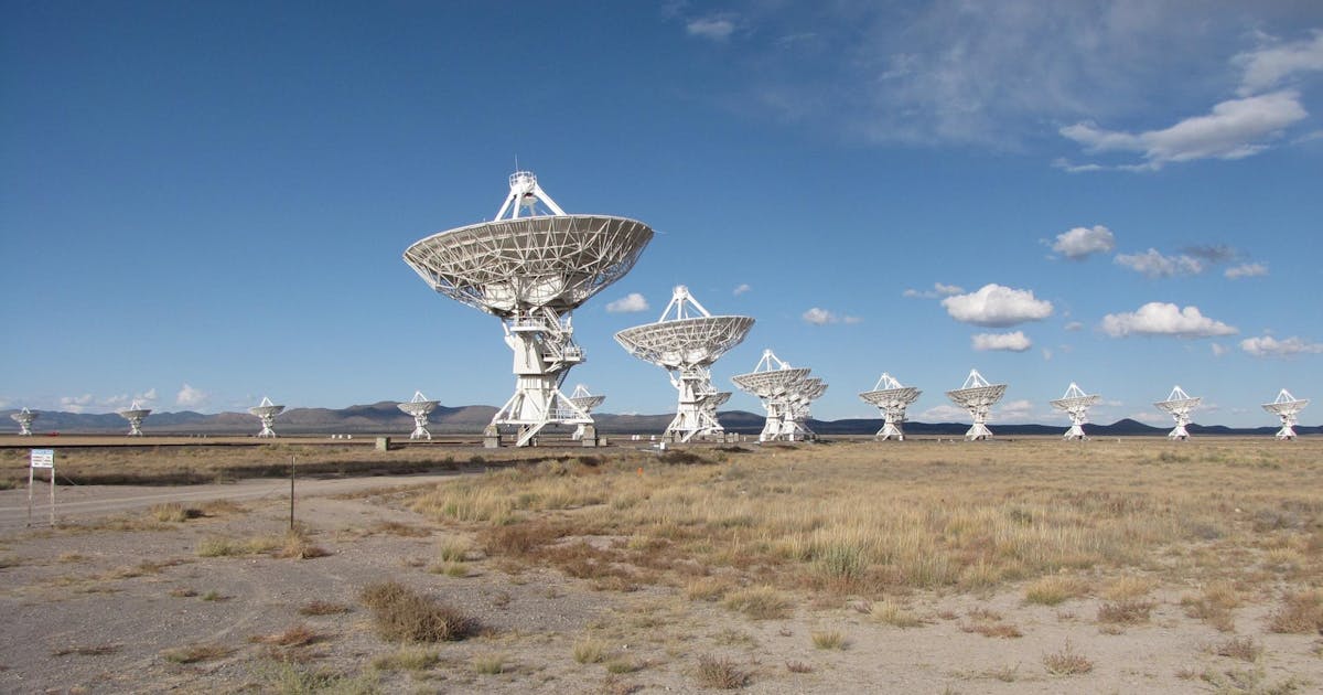 Array of radio telescopes in open terrain under a blue sky